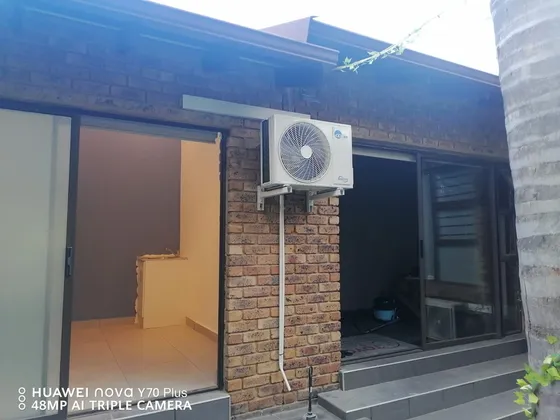A bracket-mounted outdoor air-conditioning unit beside glazed entrance doors.