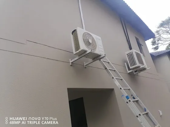 Two outdoor units mounted on exterior brackets, with an access ladder still in place.