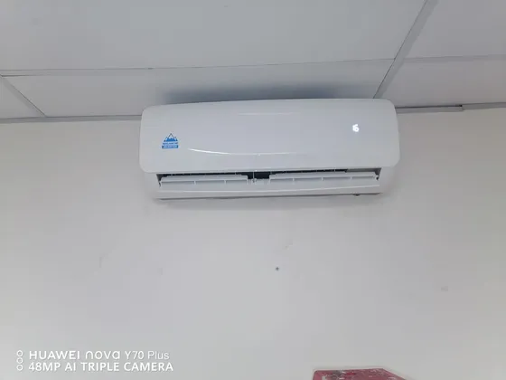 A white indoor air-conditioning unit mounted beneath a suspended ceiling.