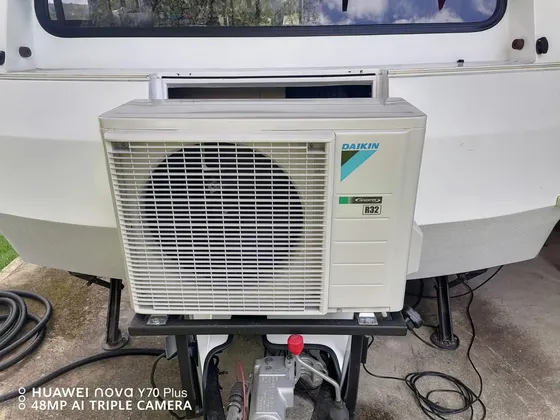 An outdoor air-conditioning unit with connected hoses during work on site.