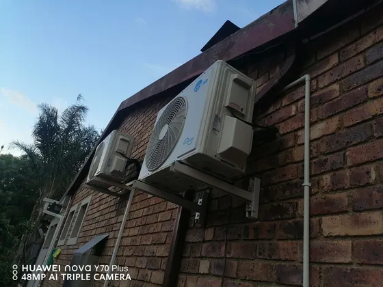 Two outdoor units mounted along a brick exterior wall.