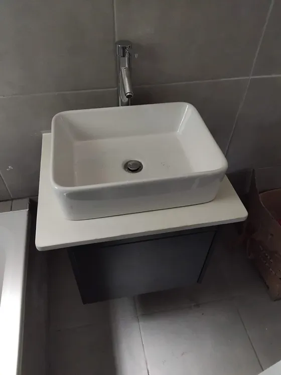 A rectangular countertop basin, tall mixer tap and dark fitted vanity.