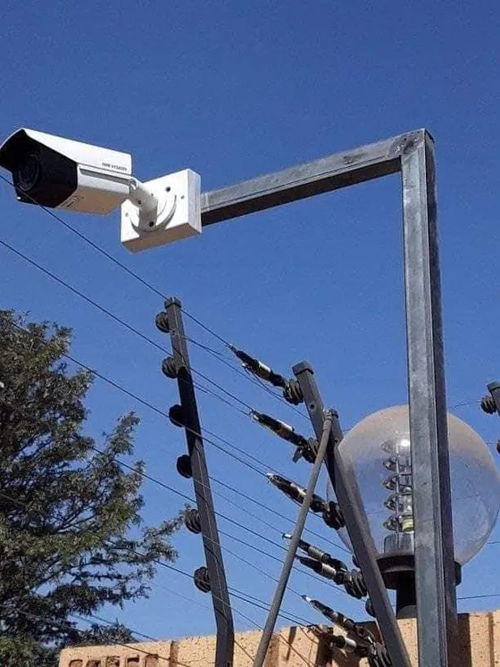 A closer view of the CCTV camera and steel mounting bracket beside the boundary fence.