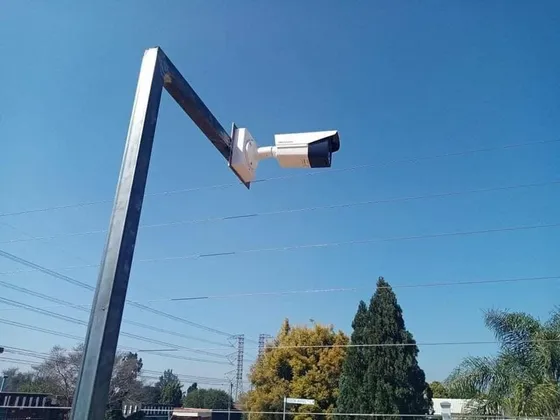 A CCTV camera mounted on an angled steel bracket above the property boundary.
