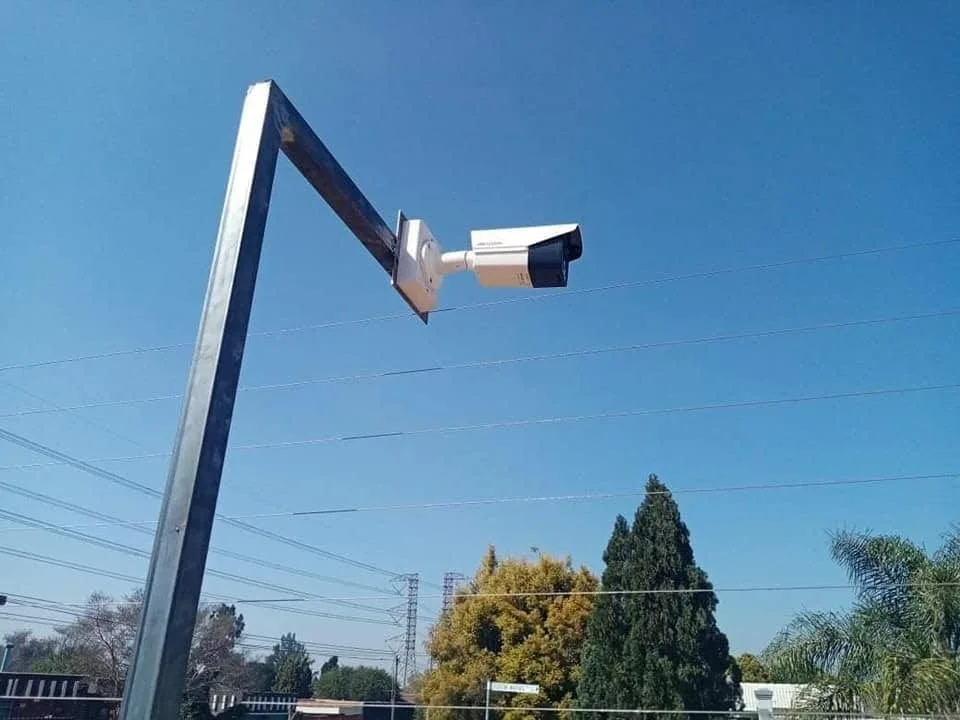 A CCTV camera mounted on an angled steel bracket above the property boundary.