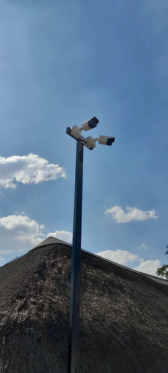 A pair of CCTV cameras positioned on a pole above the roofline.