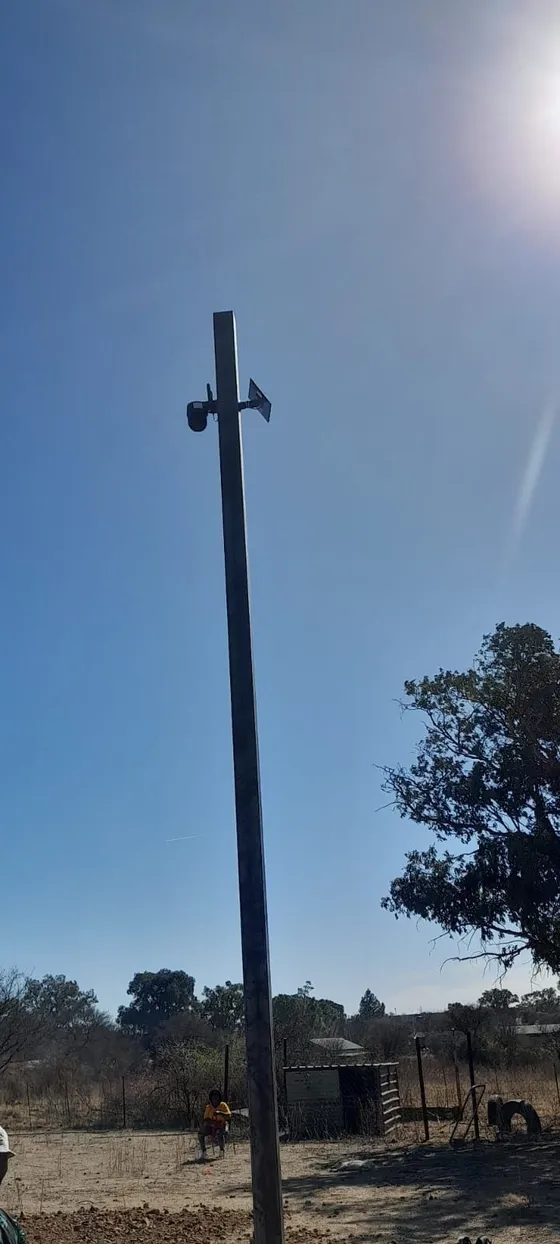 A tall camera pole viewed from ground level against the sky.