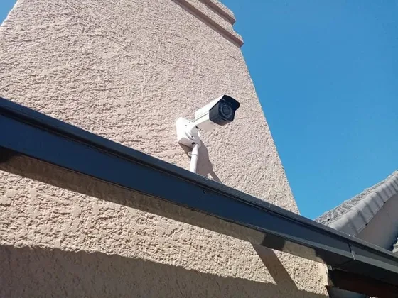 A CCTV camera fitted to a textured exterior wall above a steel beam.