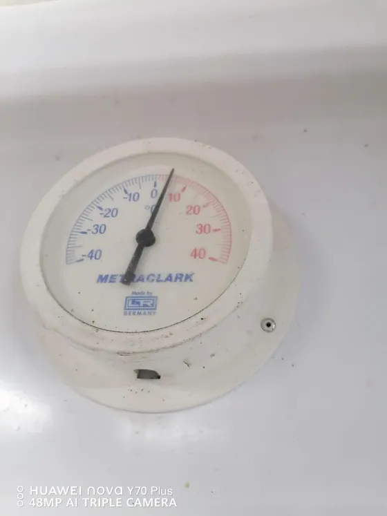 A close view of an analogue temperature gauge on a cooling enclosure.
