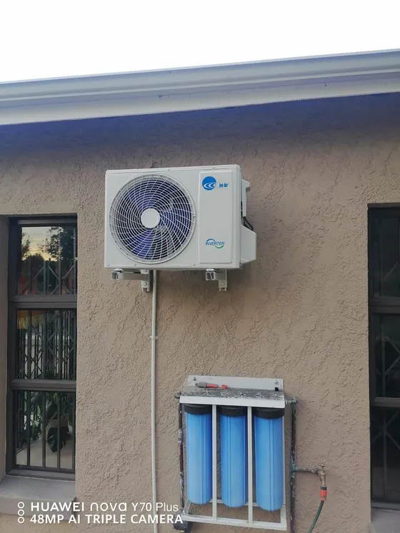 A wall-mounted filter assembly below an outdoor air-conditioning unit.
