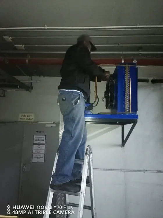 A technician fitting a wall-mounted filter assembly.
