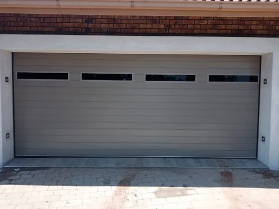 A wide grey garage door with four upper windows beneath a face-brick lintel.