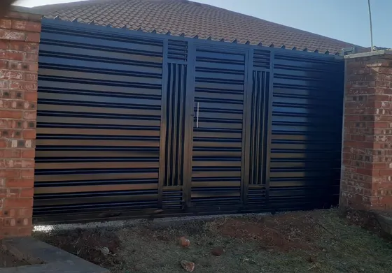 A dark slatted driveway gate with vertical accent panels between brick pillars.