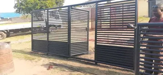 A team member working beside a wide horizontal-slatted gate during installation.