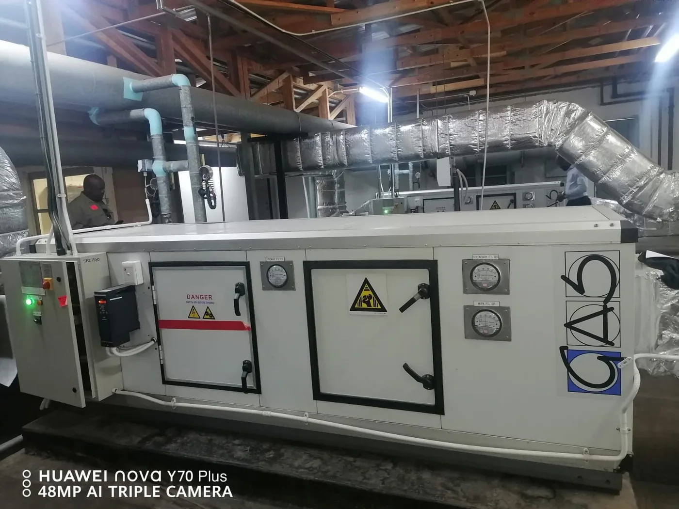Large air-handling equipment with insulated ductwork, pipe runs and filter gauges.