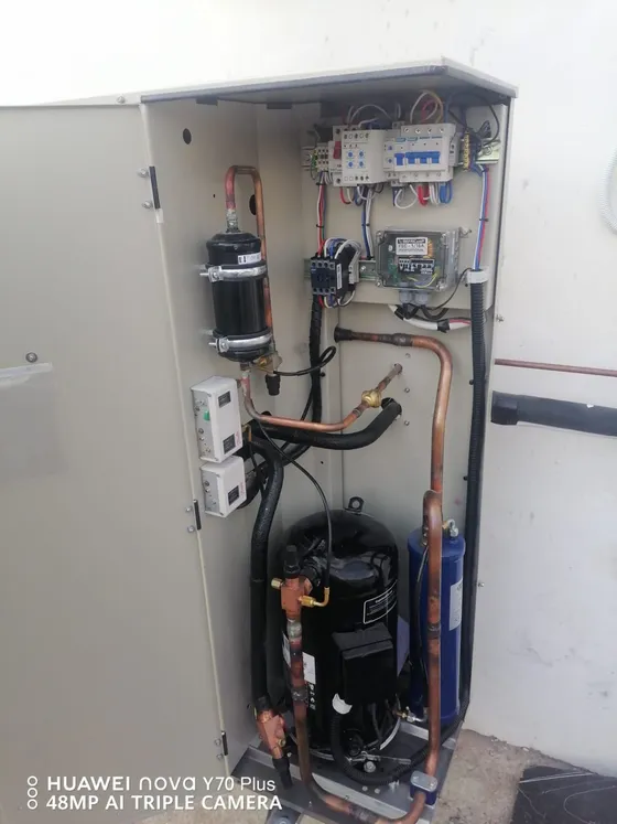 An open equipment cabinet showing its electrical components and pipework.