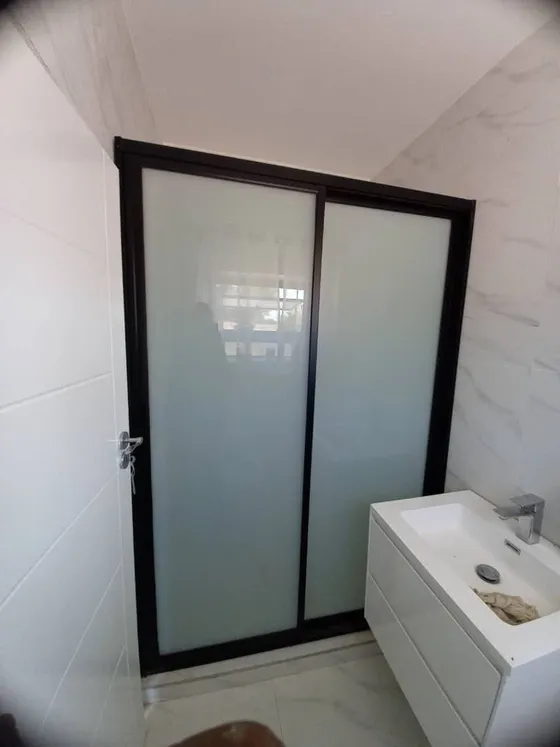 A closer view of a frosted-glass enclosure and tiled bathroom.