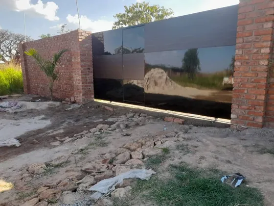 A dark sliding gate between brick entrance pillars.