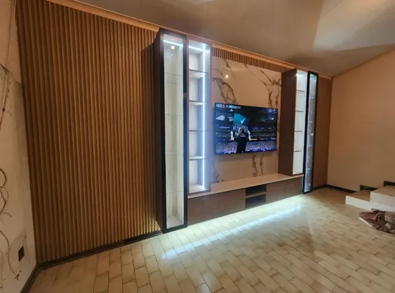 A television feature wall with timber-look panels and illuminated display cabinets.