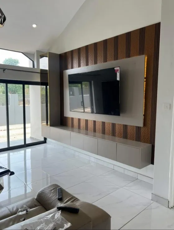 A wall-mounted television on a panelled feature wall with a floating cabinet.