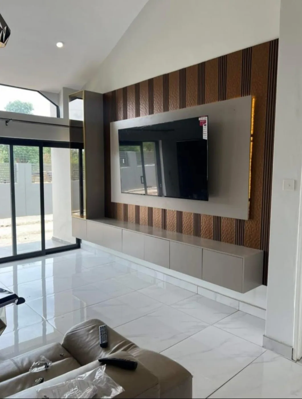 A wall-mounted television on a panelled feature wall with a floating cabinet.