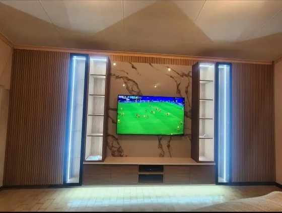 A television wall with illuminated display cabinets and a low storage unit.