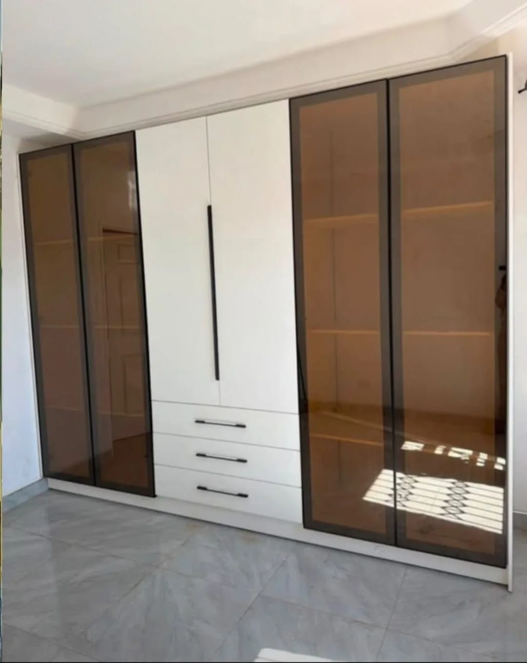 Built-in wardrobes with a mix of light doors, drawers and darker panels.