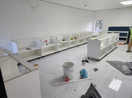 Base cupboards being fitted along the walls of a kitchen.