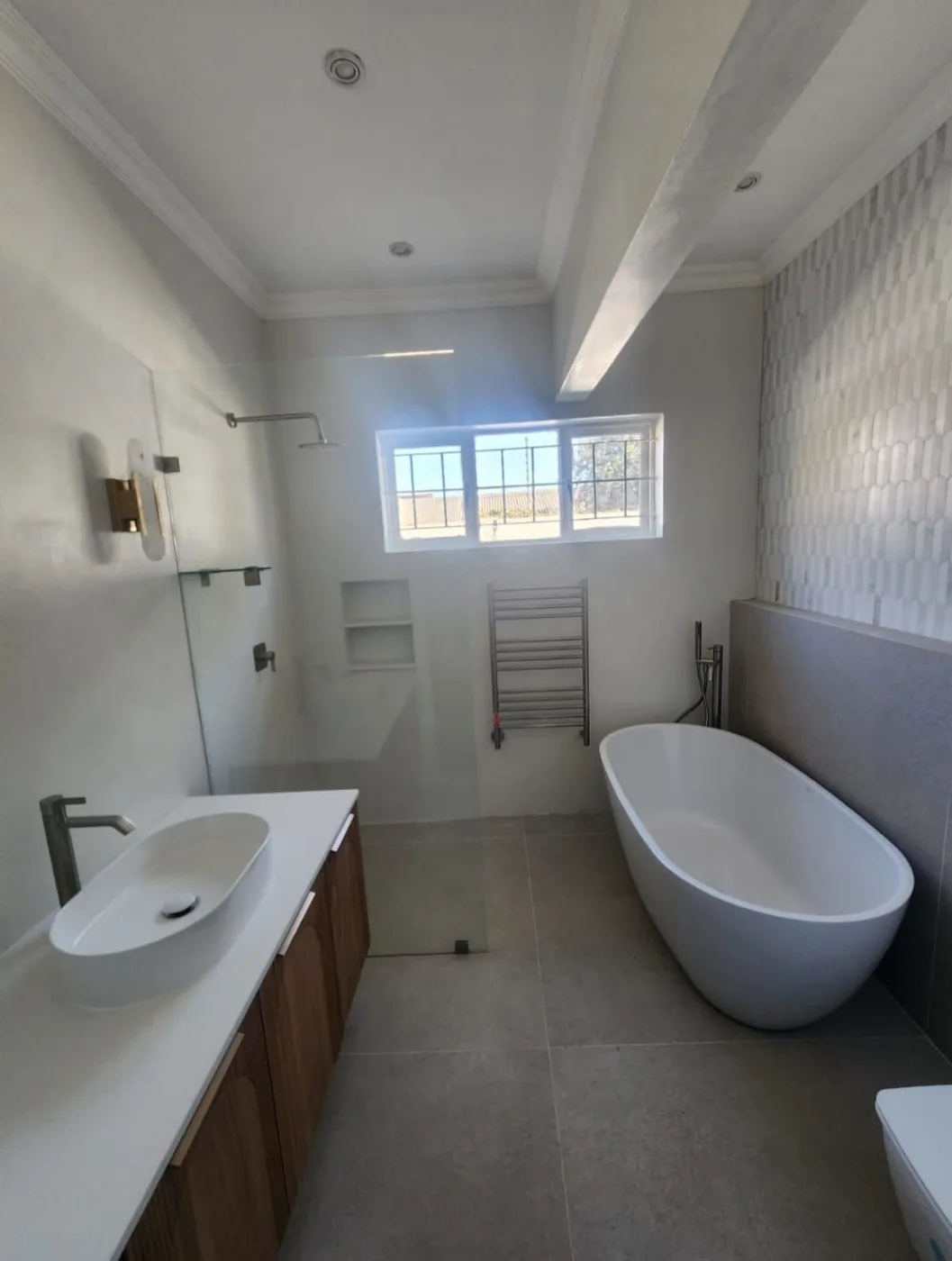 A freestanding bath and vanity in a tiled bathroom.