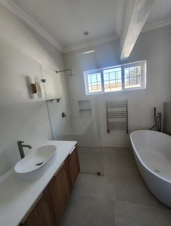 A tiled bathroom with a vanity and bath photographed from the doorway.