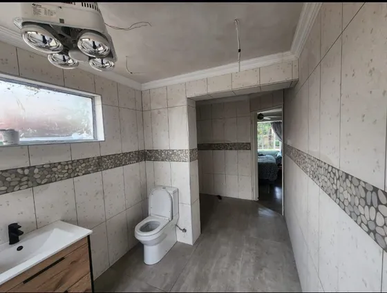A tiled bathroom with basin, toilet, shower enclosure and ceiling fittings.