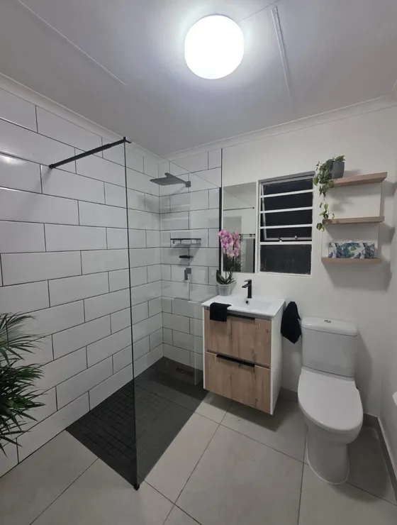 A basin, toilet and shower area with contrasting floor and wall tiles.