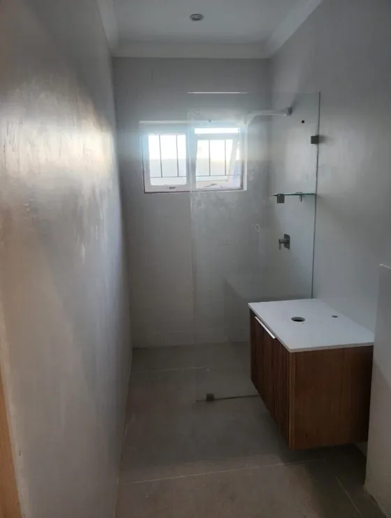 A bathroom with a glass shower screen and timber-look vanity cabinet.