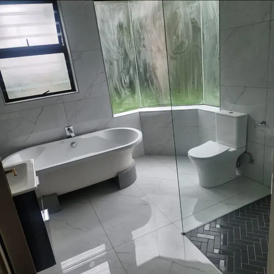 A freestanding bath, wall-mounted toilet and glazed shower screen.