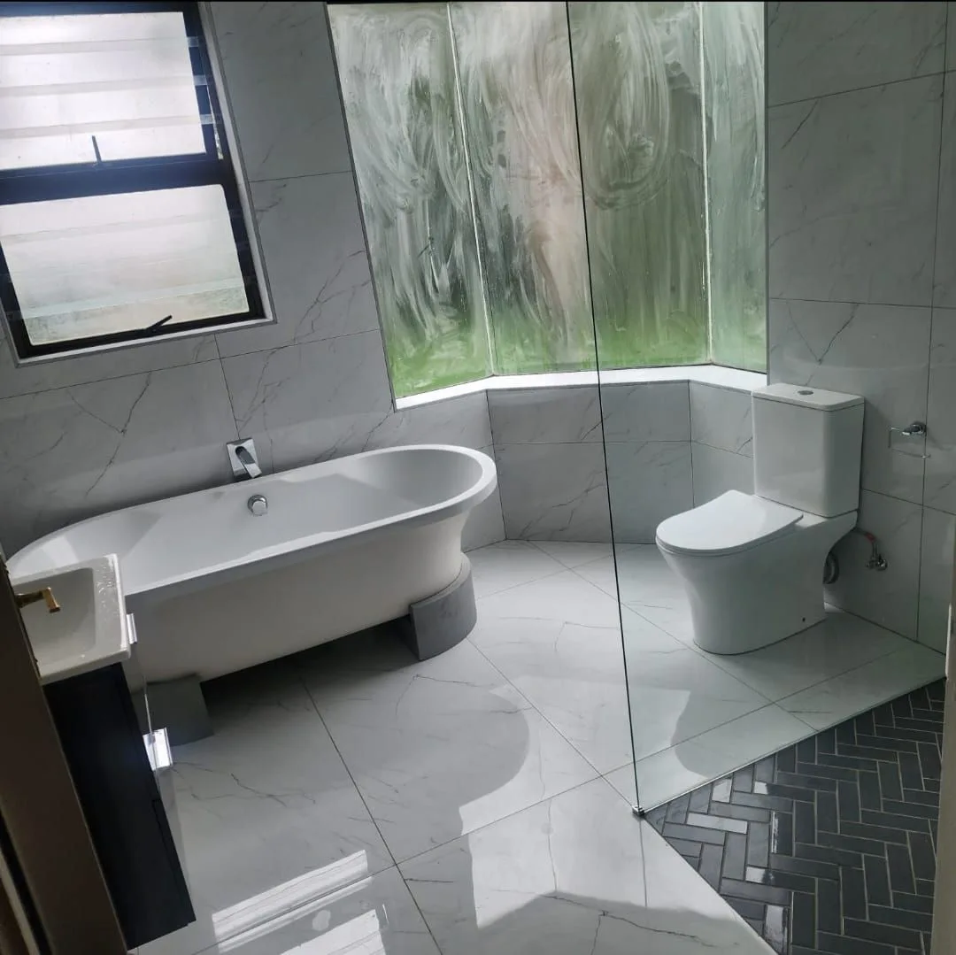 A freestanding bath, wall-mounted toilet and glazed shower screen.