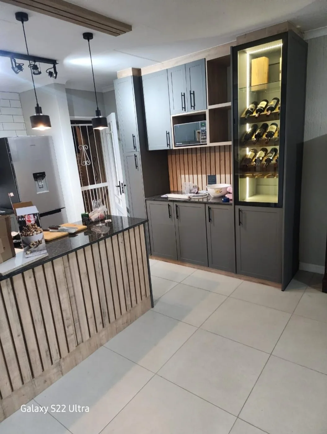 Kitchen cupboards, a breakfast counter and an illuminated display cabinet.