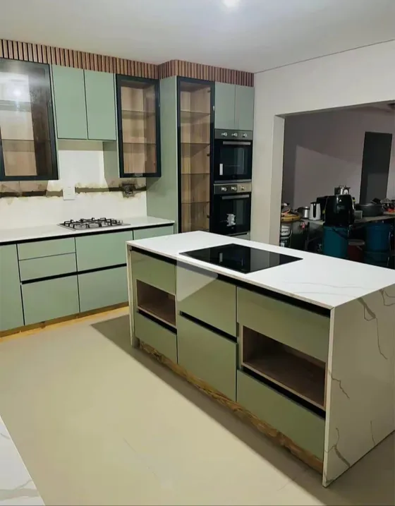 A kitchen island with a hob, pale cupboards and contrasting work surfaces.