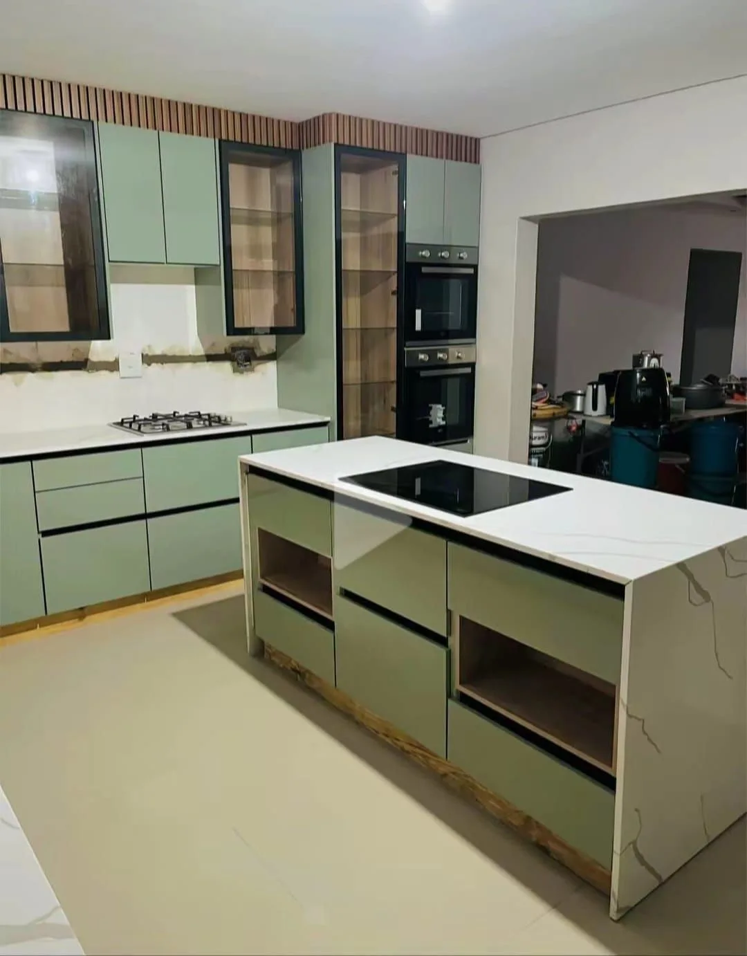 A kitchen island with a hob, pale cupboards and contrasting work surfaces.