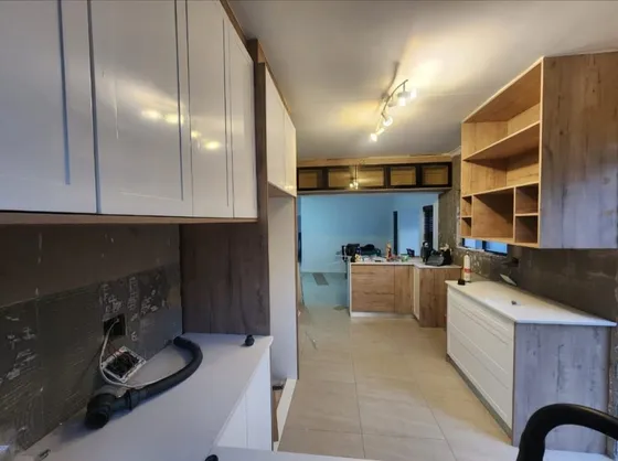 A kitchen with fitted cupboards, open shelving and light worktops.